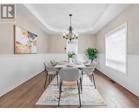 A dining room with a chandelier, a table with chairs, and a rug on the floor.