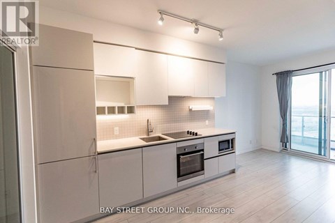 A modern kitchen with white cabinets and a large window.