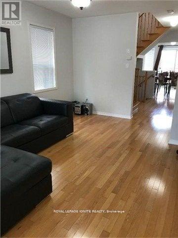 A living room with a black couch and wooden floors.