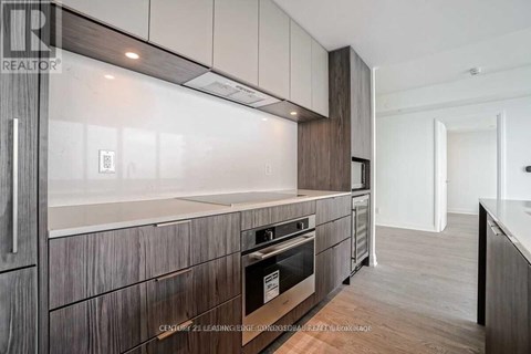 A modern kitchen with dark wood cabinets and a stainless steel oven.