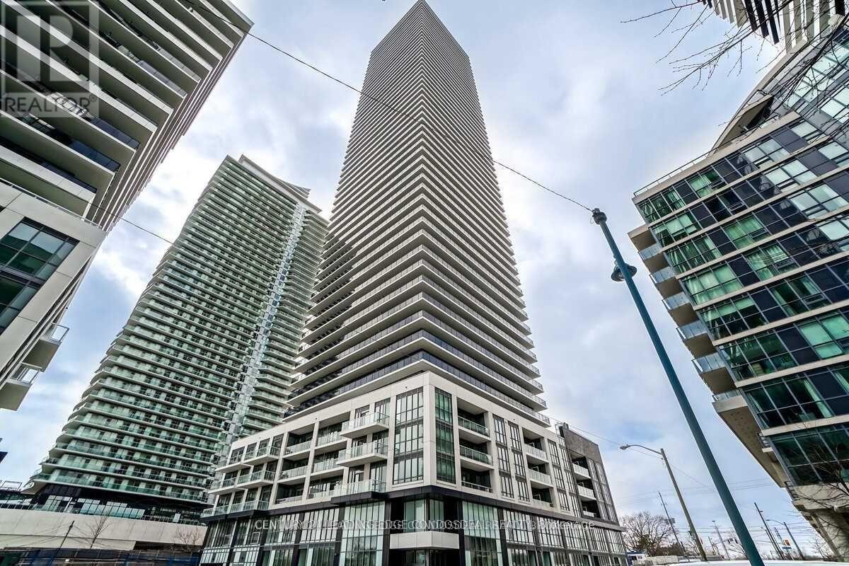 A tall building with a pointed top stands in front of other buildings.