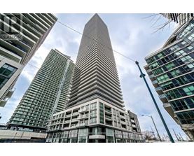 A tall building with a pointed top stands in front of other buildings.