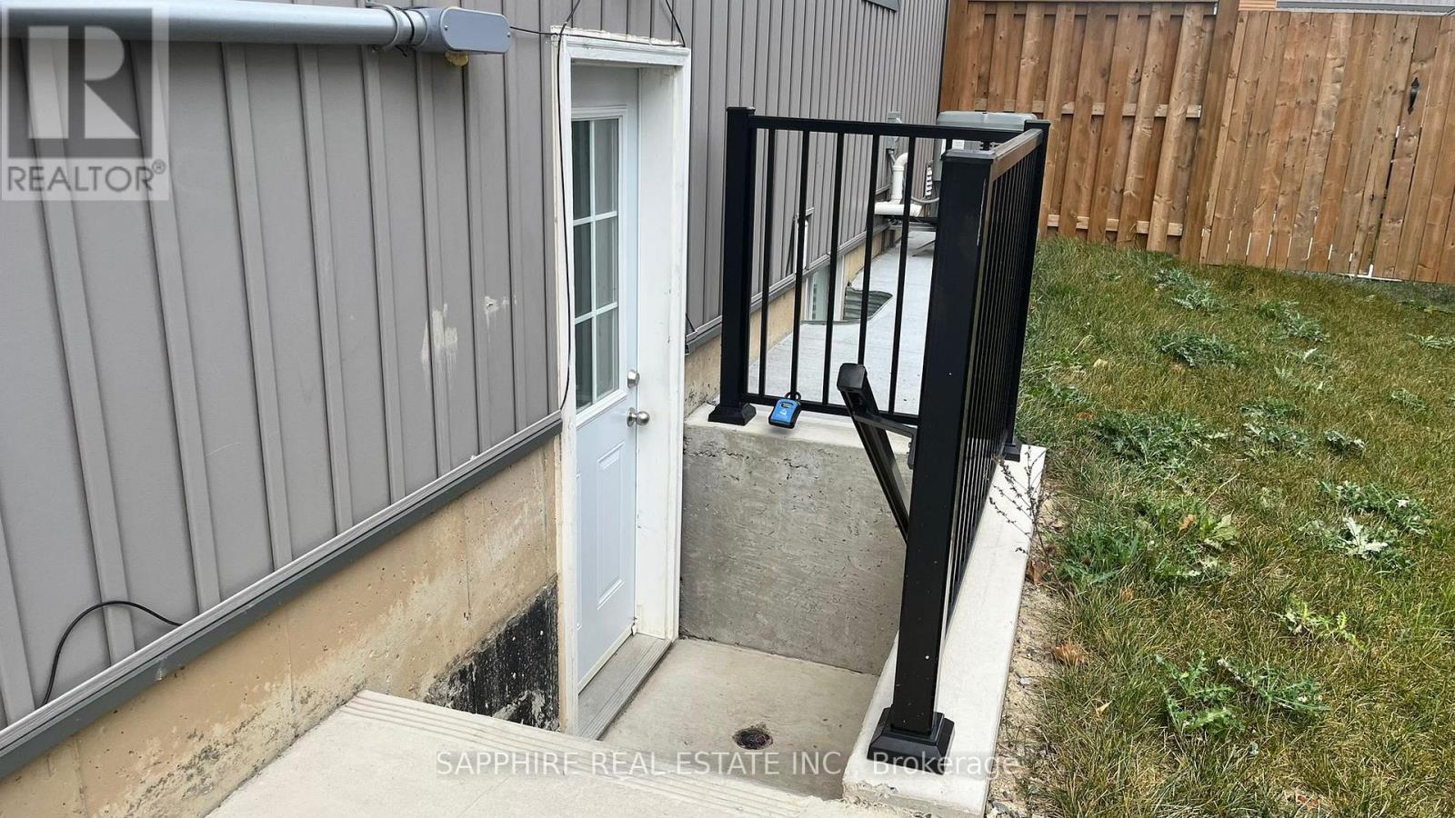 A small white door is open to a concrete step.