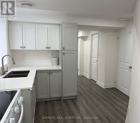 A kitchen with white cabinets and a grey countertop.