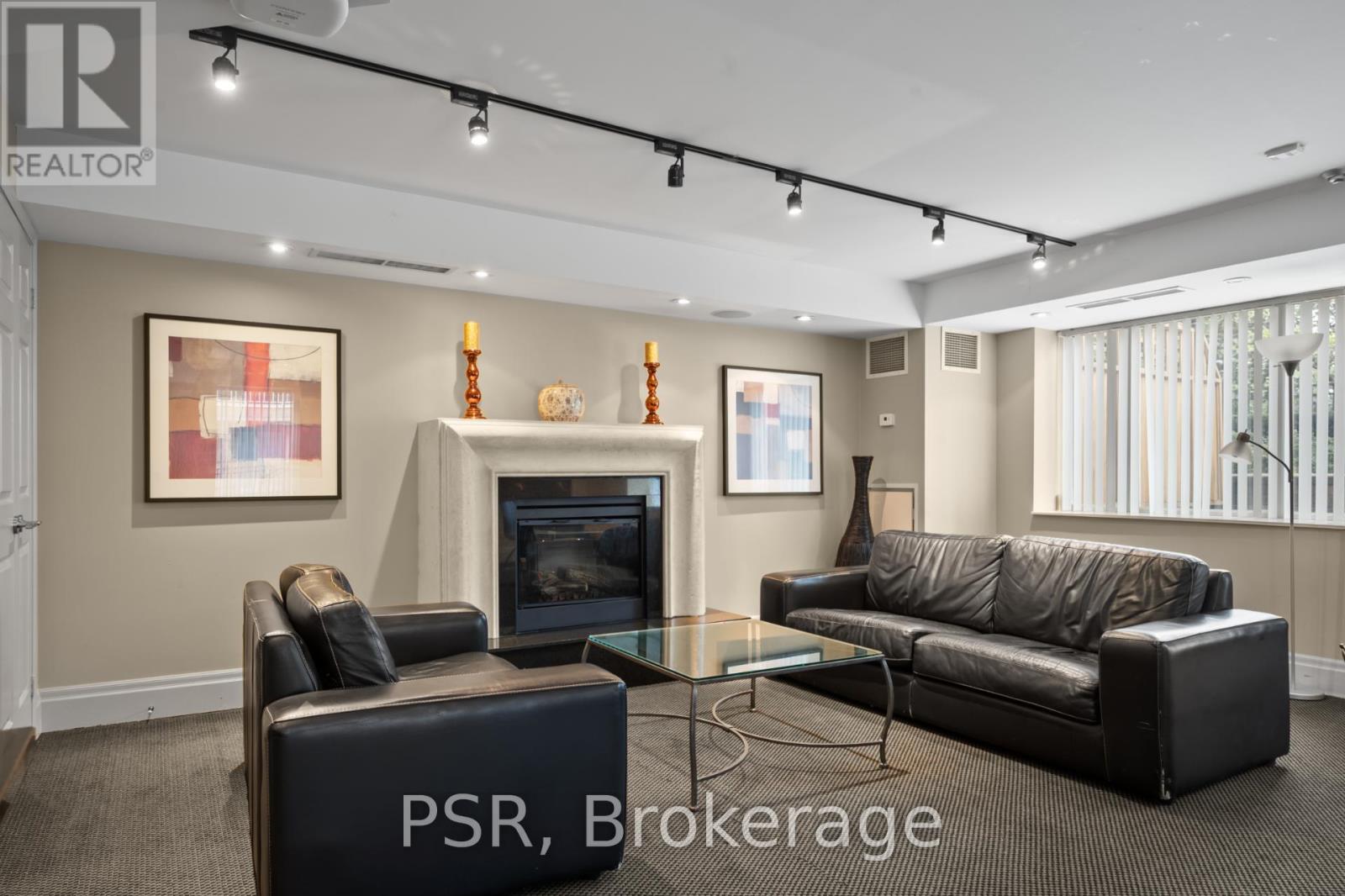 A living room with a black leather couch and a glass coffee table.