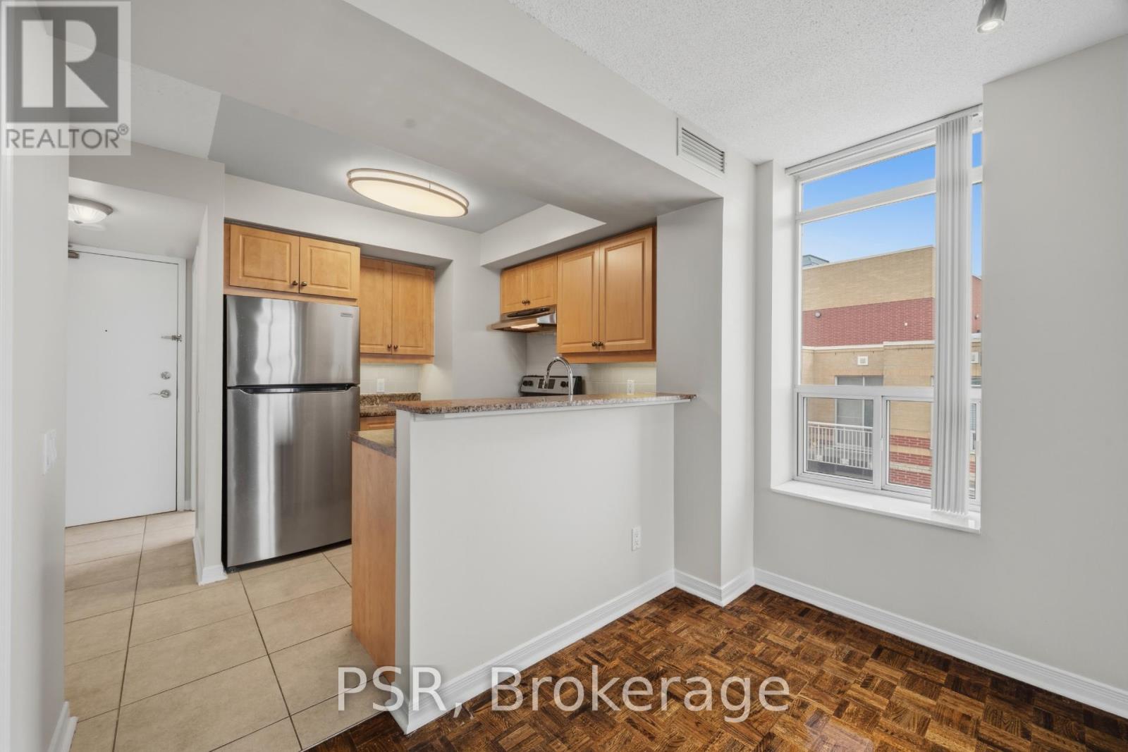 A kitchen with wooden cabinets and a stainless steel refrigerator.