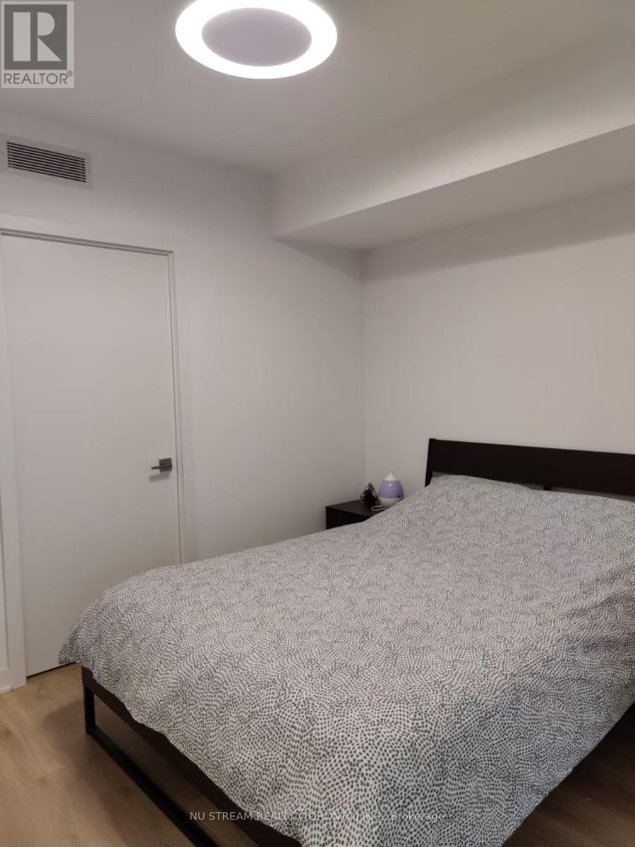 A bedroom with a bed, nightstand, and a door.