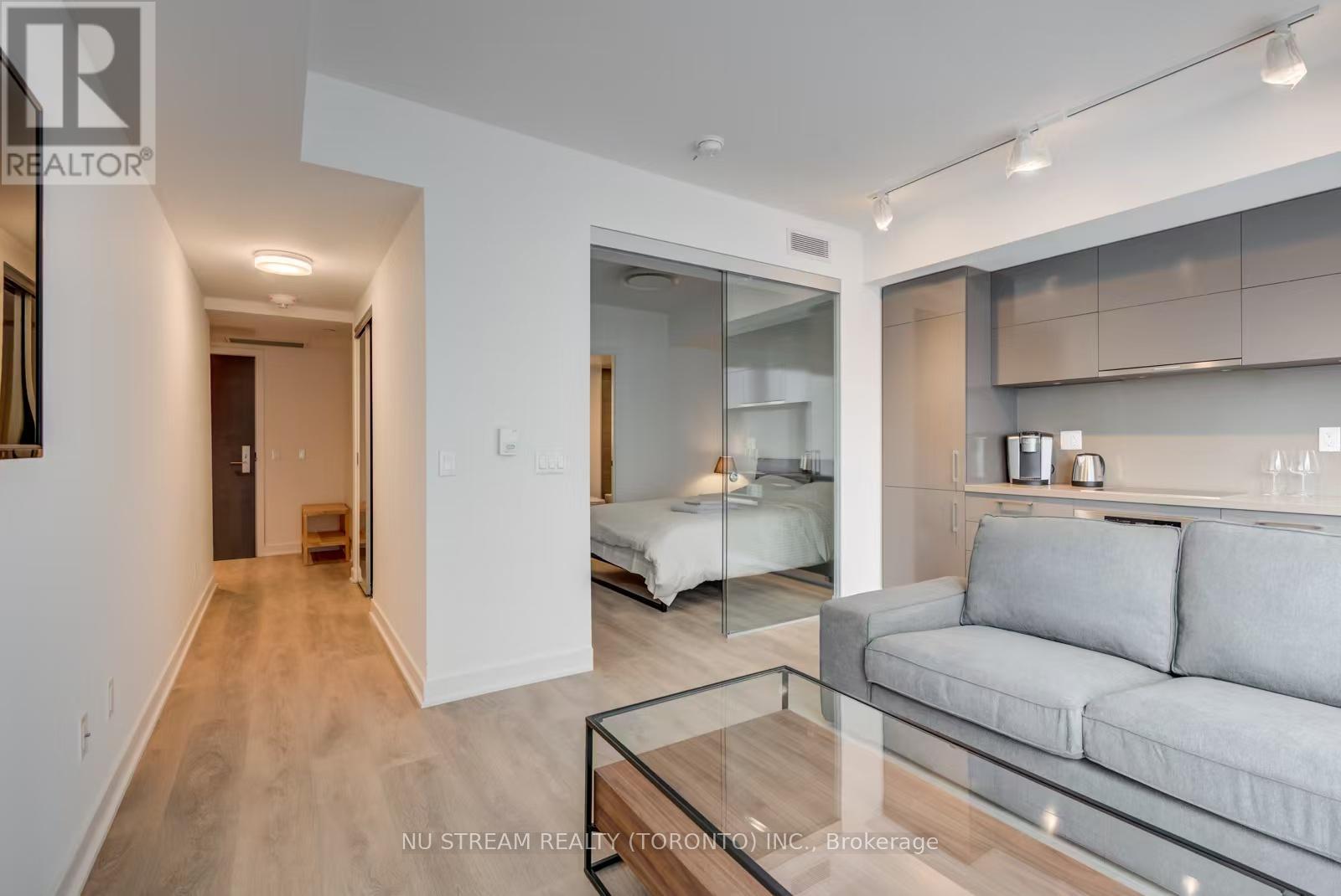 A modern living room with a glass coffee table and a grey couch.