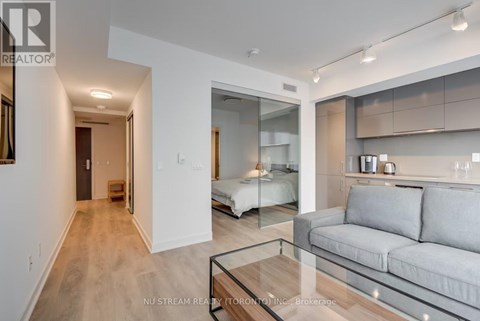 A modern living room with a glass coffee table and a grey couch.