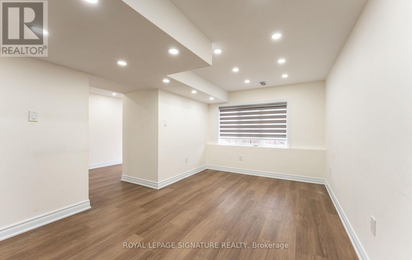 A spacious room with wooden flooring and white walls.