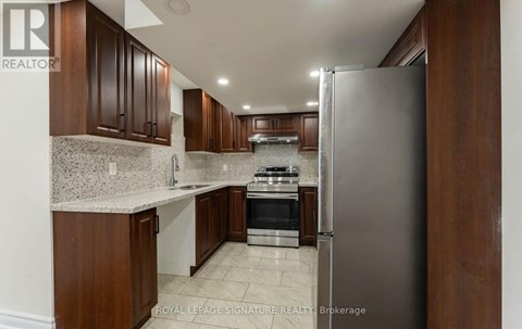 A kitchen with brown cabinets and a refrigerator.