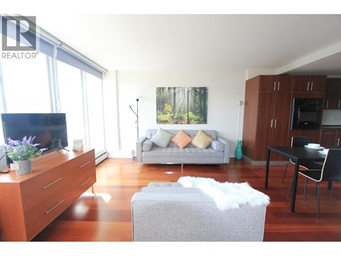 A living room with a grey couch and a wooden cabinet.