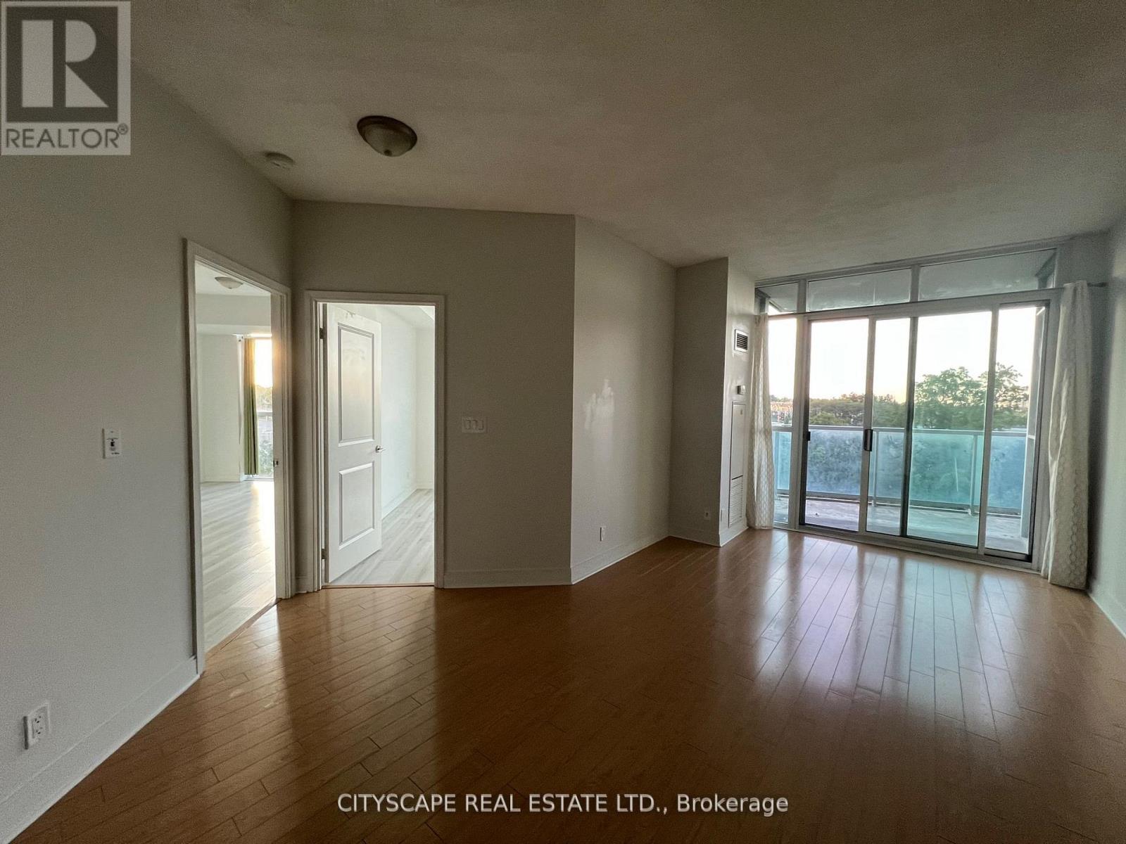 A spacious room with wooden floors and large windows.