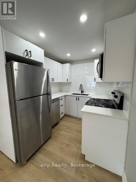 A kitchen with a refrigerator, stove, and cabinets.