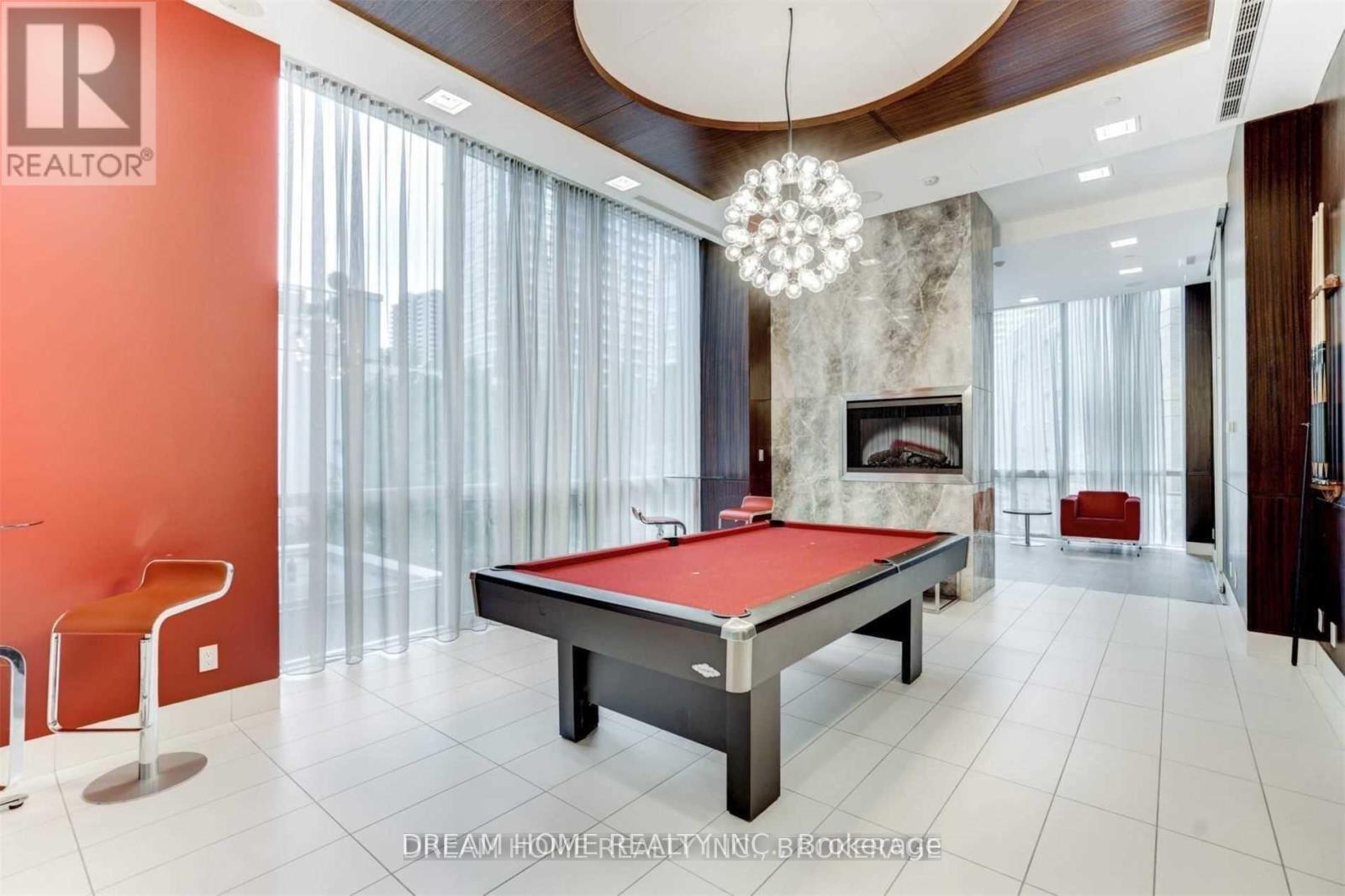 A pool table in a room with a fireplace and a chandelier.