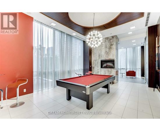A pool table in a room with a fireplace and a chandelier.