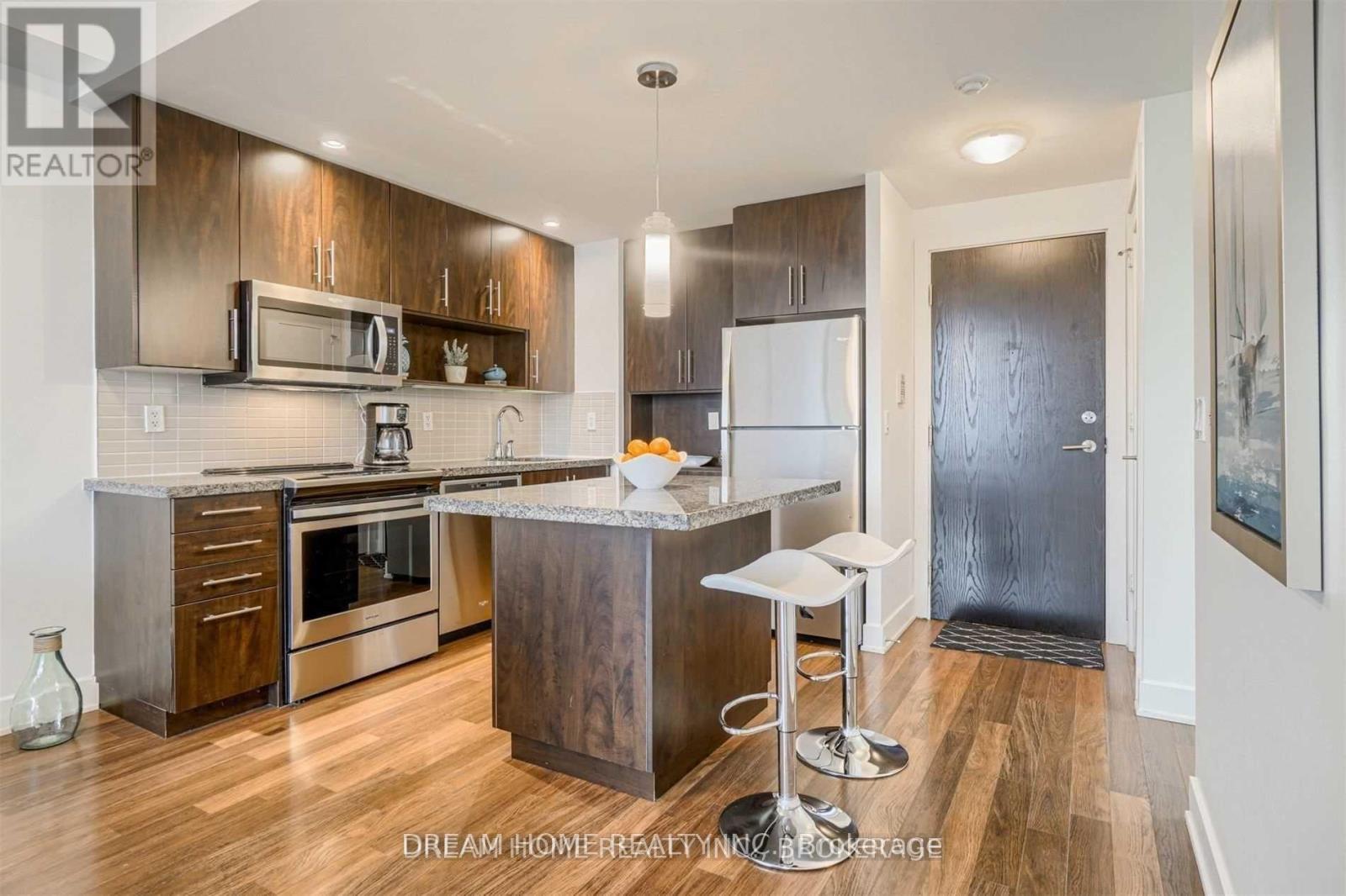 A modern kitchen with wood floors and stainless steel appliances.