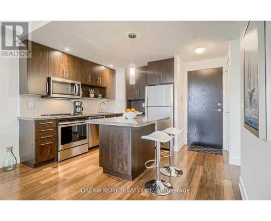A modern kitchen with wood floors and stainless steel appliances.