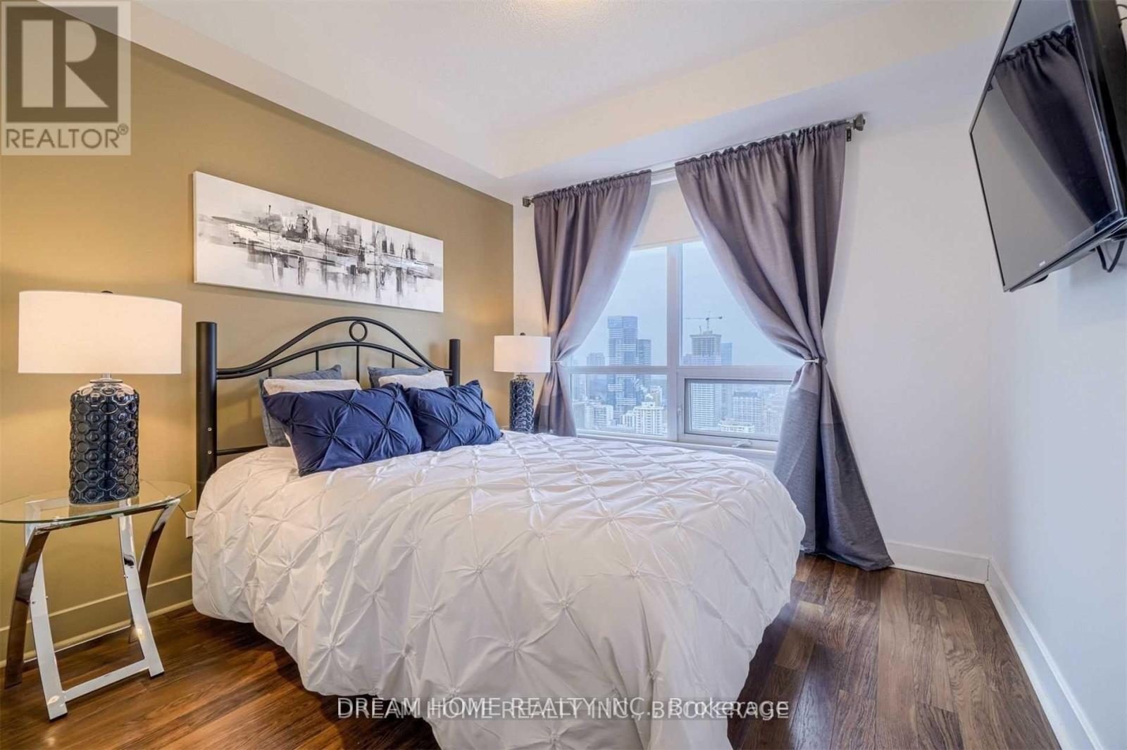A bedroom with a large bed and a flat screen TV mounted on the wall.