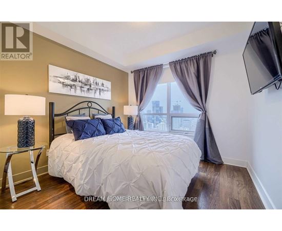 A bedroom with a large bed and a flat screen TV mounted on the wall.
