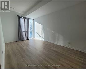 A room with wooden flooring and a window with curtains.