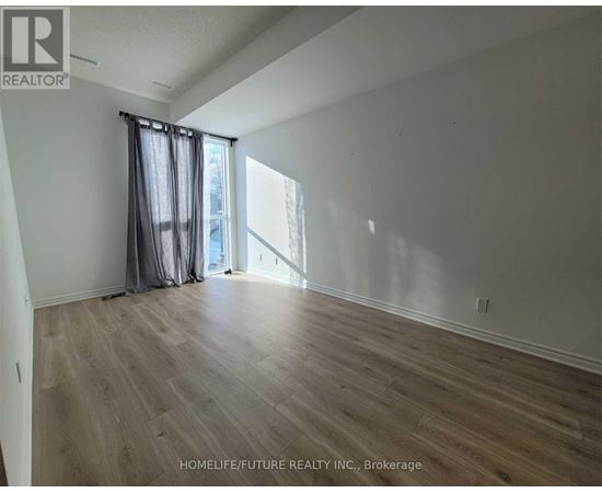 A room with wooden flooring and a window with curtains.