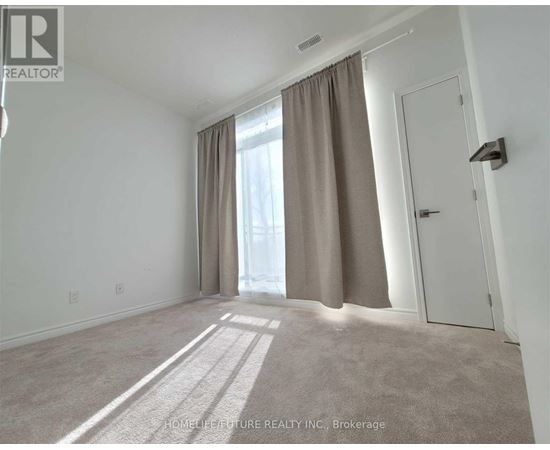 A room with a carpeted floor, a door, and a window with curtains.