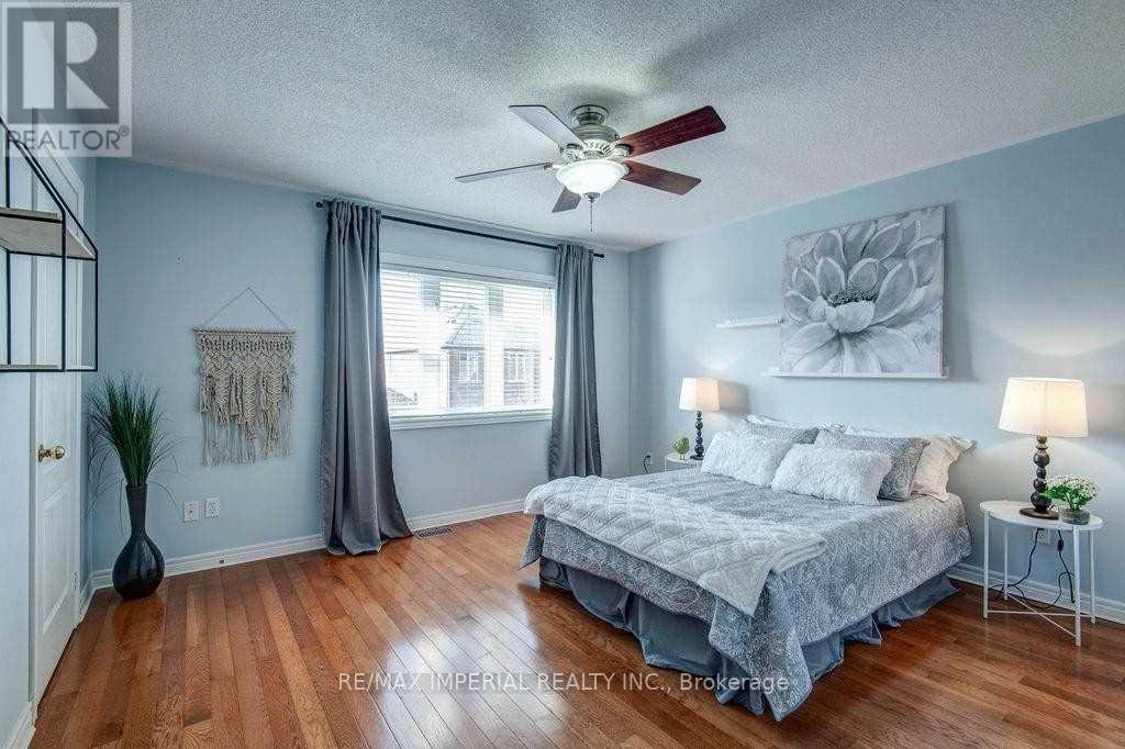 A bedroom with a bed, a ceiling fan, and a lamp.