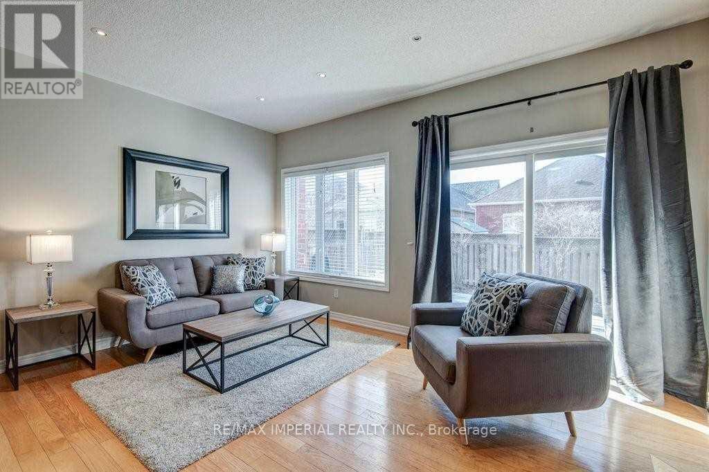 A living room with a grey couch, a coffee table, and a large window with curtains.