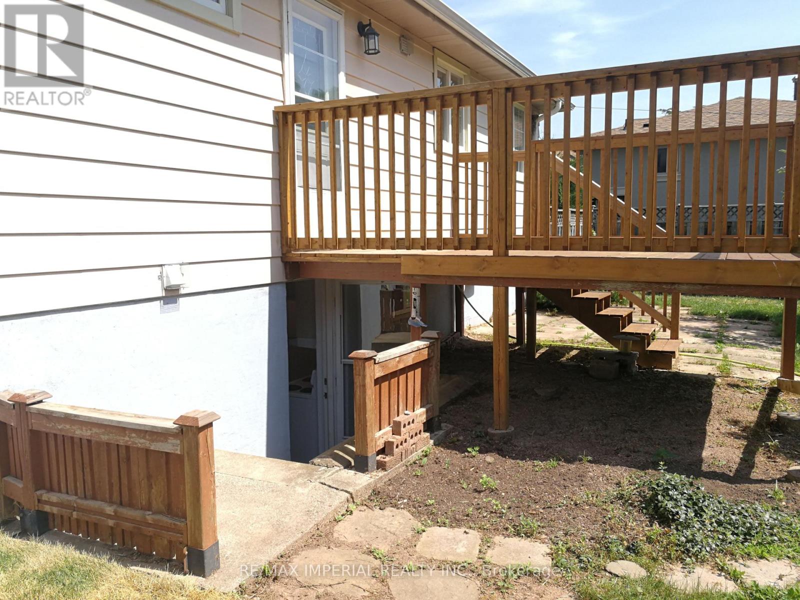 A wooden deck with a railing and steps leading to a house.