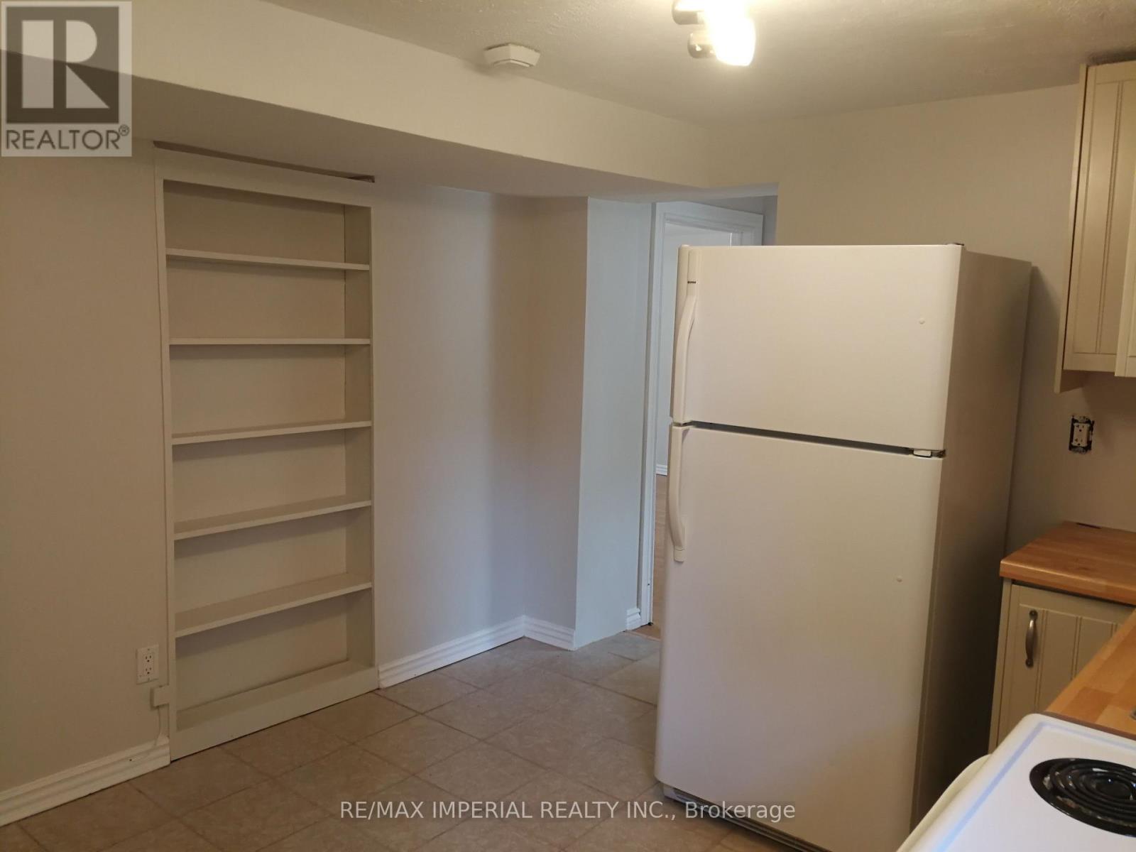 A white refrigerator in a kitchen with a white wall and a white door.