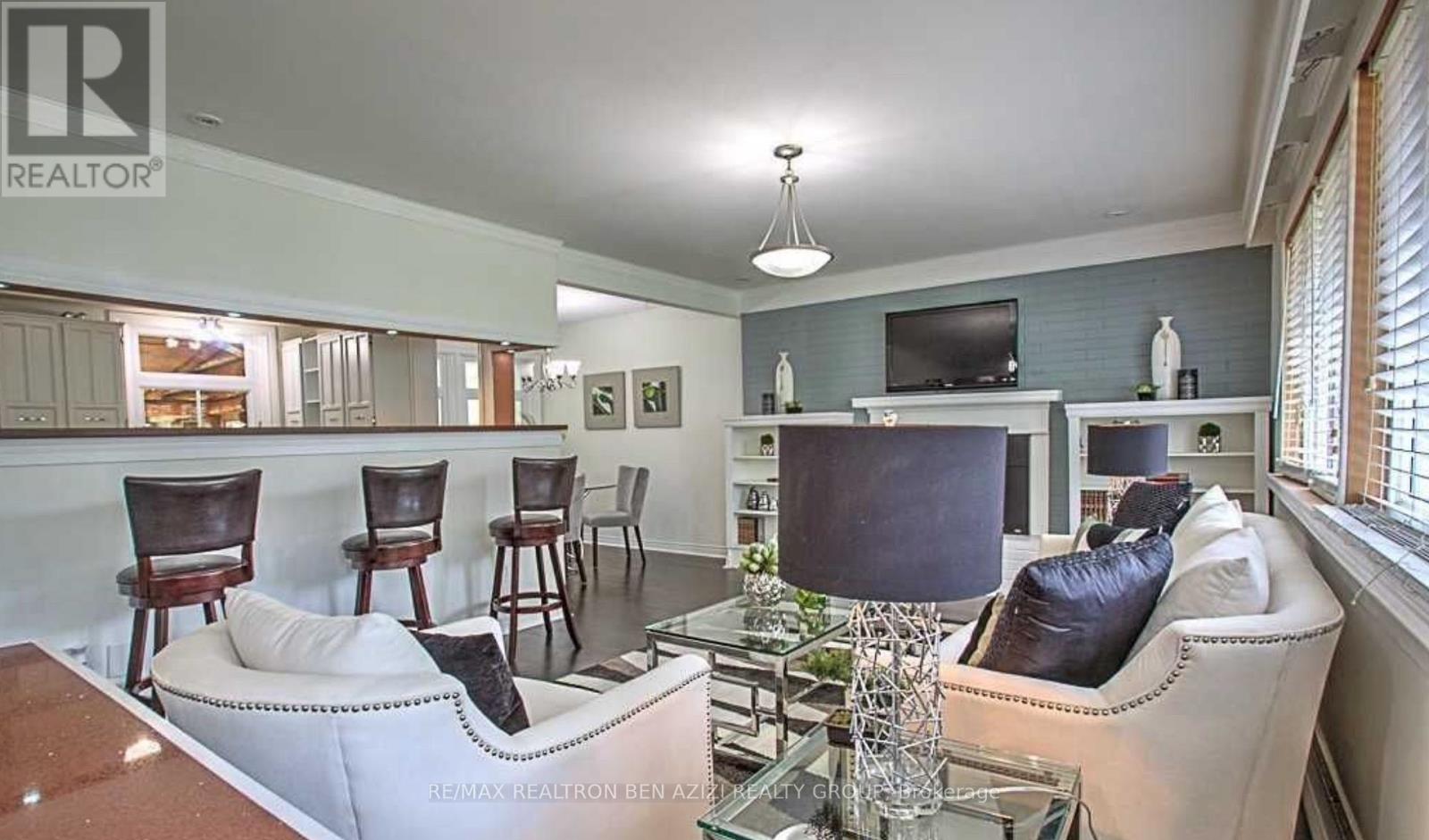 A living room with a couch, chairs, and a television.