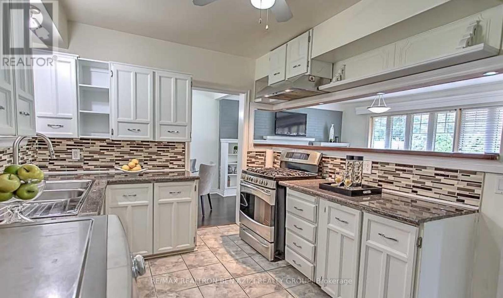 A kitchen with white cabinets and a stone backsplash.