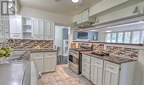 A kitchen with white cabinets and a stone backsplash.