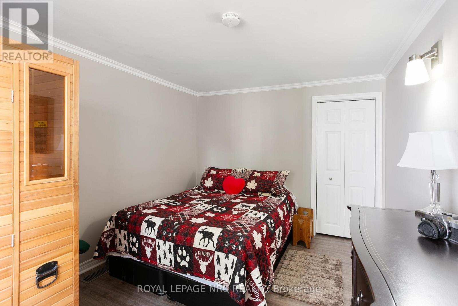 A bedroom with a bed covered in a red and white patterned bedspread.