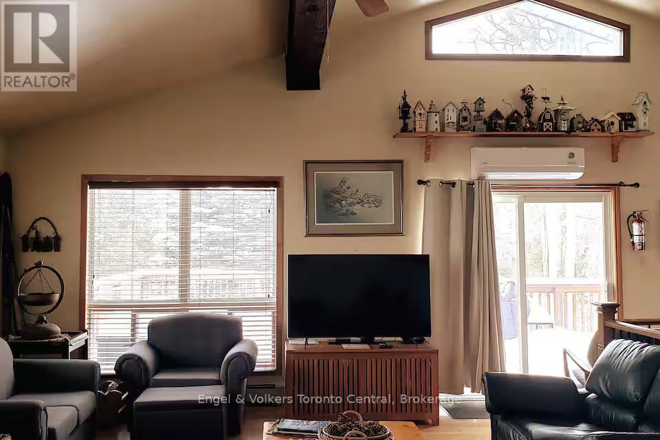 A living room with a black leather couch and a flat screen TV.