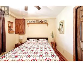A bedroom with a bed covered in a red and white quilt.