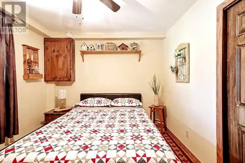 A bedroom with a bed covered in a red and white quilt.