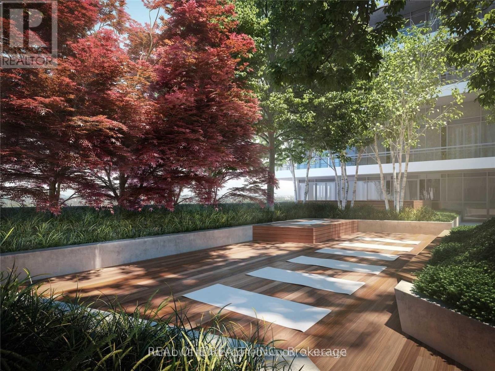 A modern outdoor space with wooden decking and a variety of trees.