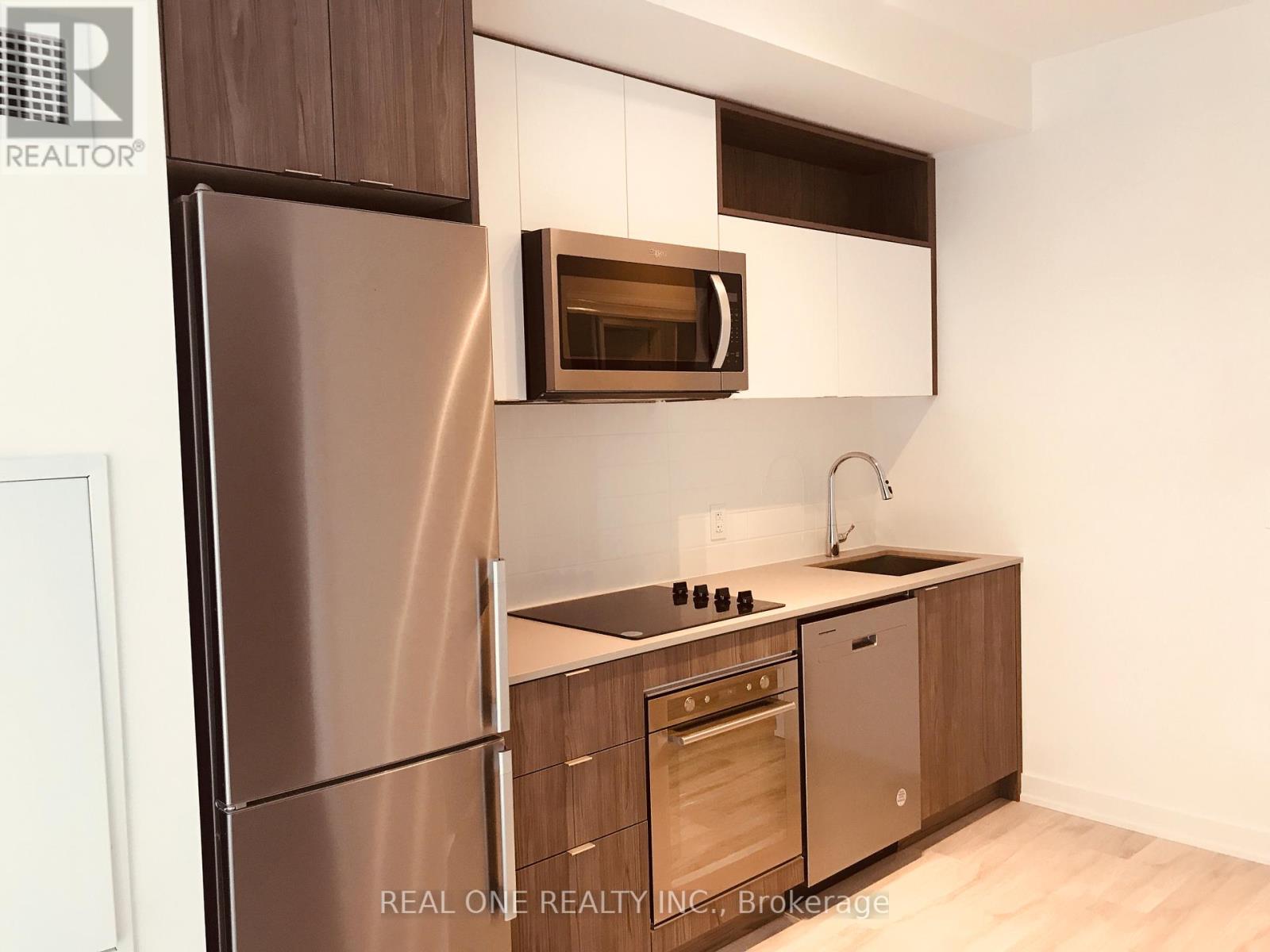 A modern kitchen with a stainless steel refrigerator and wooden cabinets.