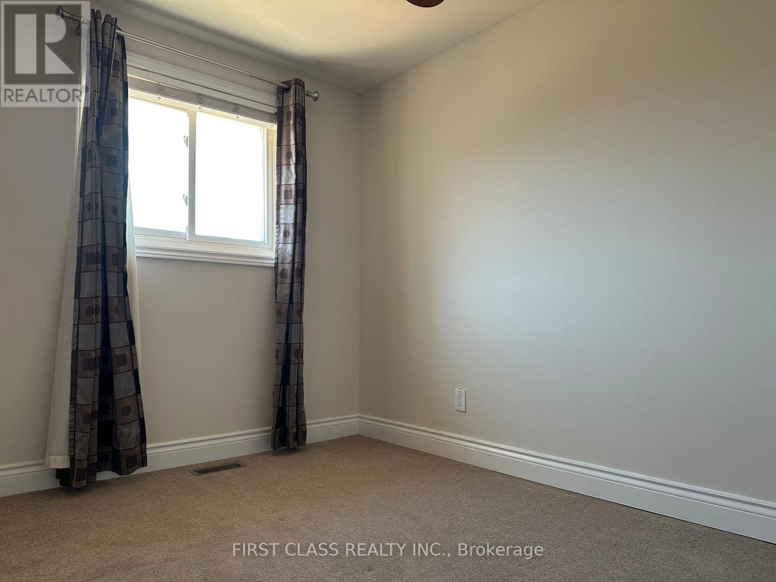 A room with a window and curtains, with a carpet on the floor.