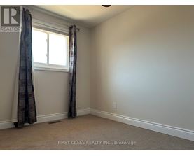 A room with a window and curtains, with a carpet on the floor.