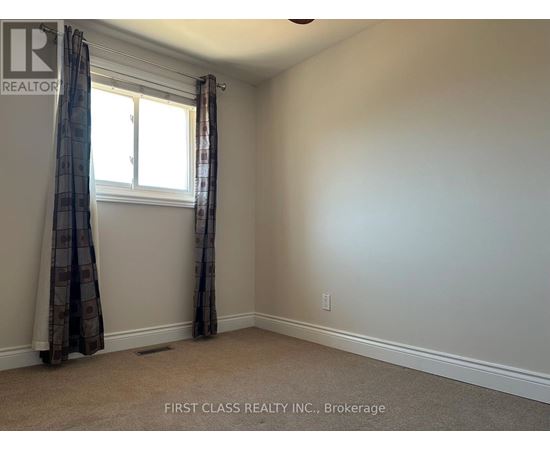 A room with a window and curtains, with a carpet on the floor.