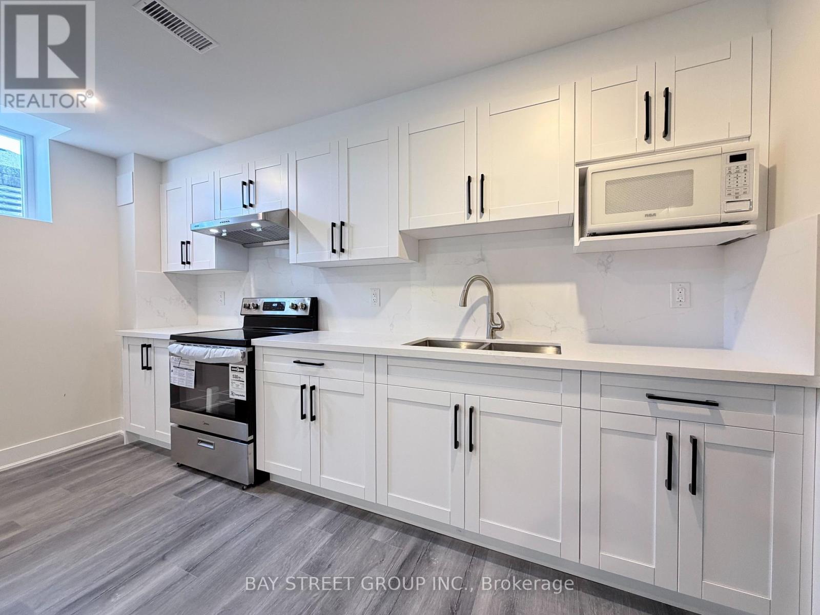 A kitchen with white cabinets and a microwave above the sink.