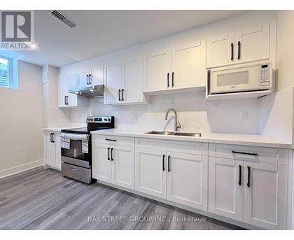 A kitchen with white cabinets and a microwave above the sink.