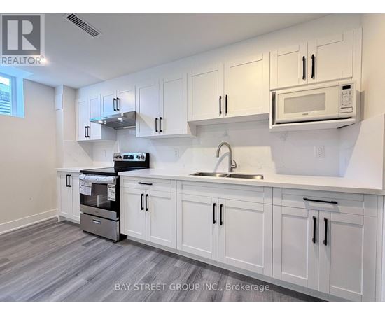 A kitchen with white cabinets and a microwave above the sink.