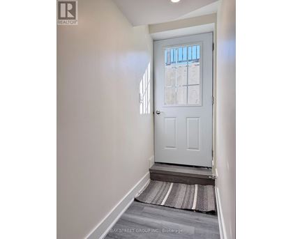A white door with a glass window is in a hallway with a striped rug on the floor.