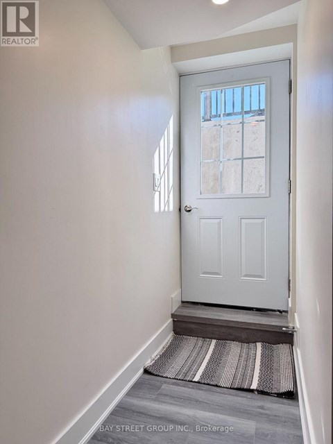 A white door with a glass window is in a hallway with a striped rug on the floor.