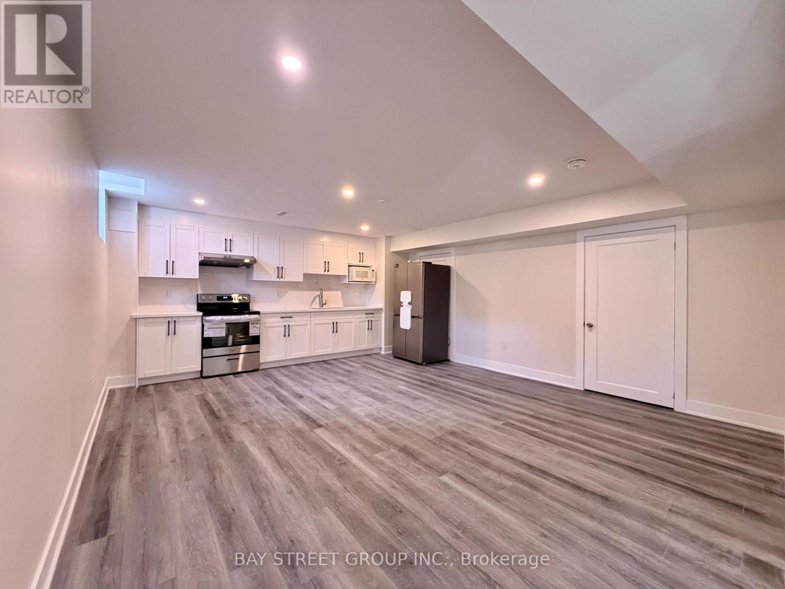 A spacious kitchen with white cabinets and a grey floor.