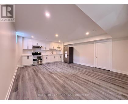 A spacious kitchen with white cabinets and a grey floor.